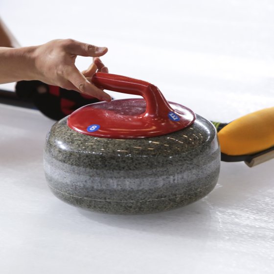 Punainen curlingkivi heitetään