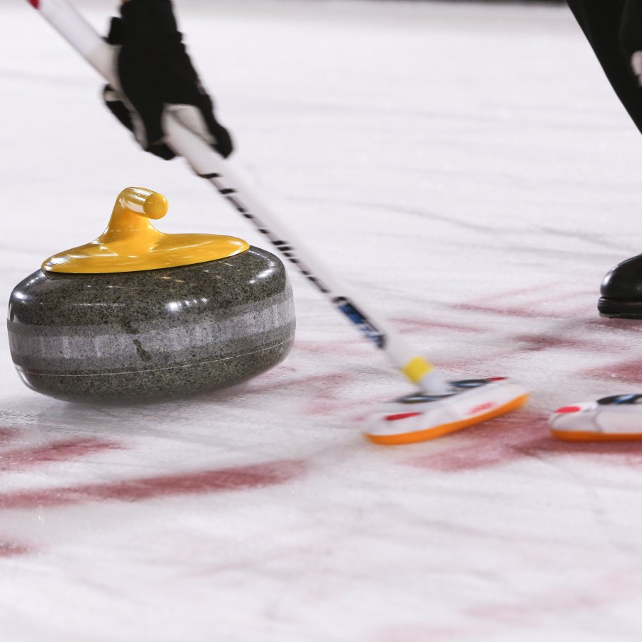 Keltaista curlingkiveä harjataan